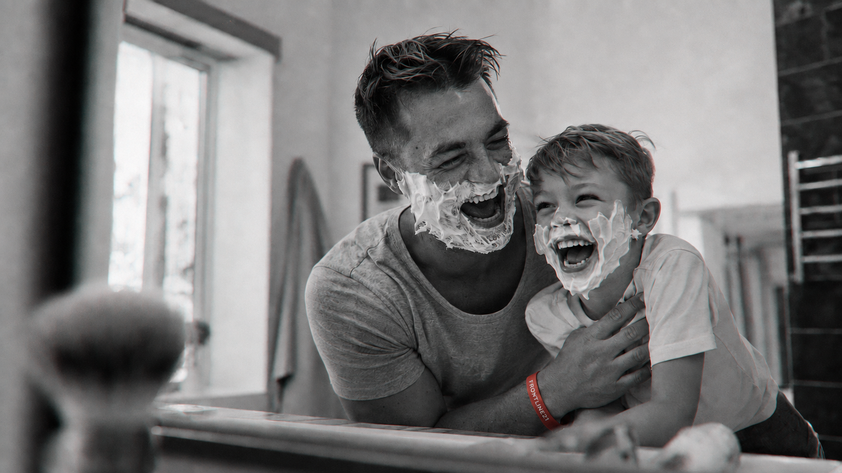 A father and son at the mirror, the red band on his wrist