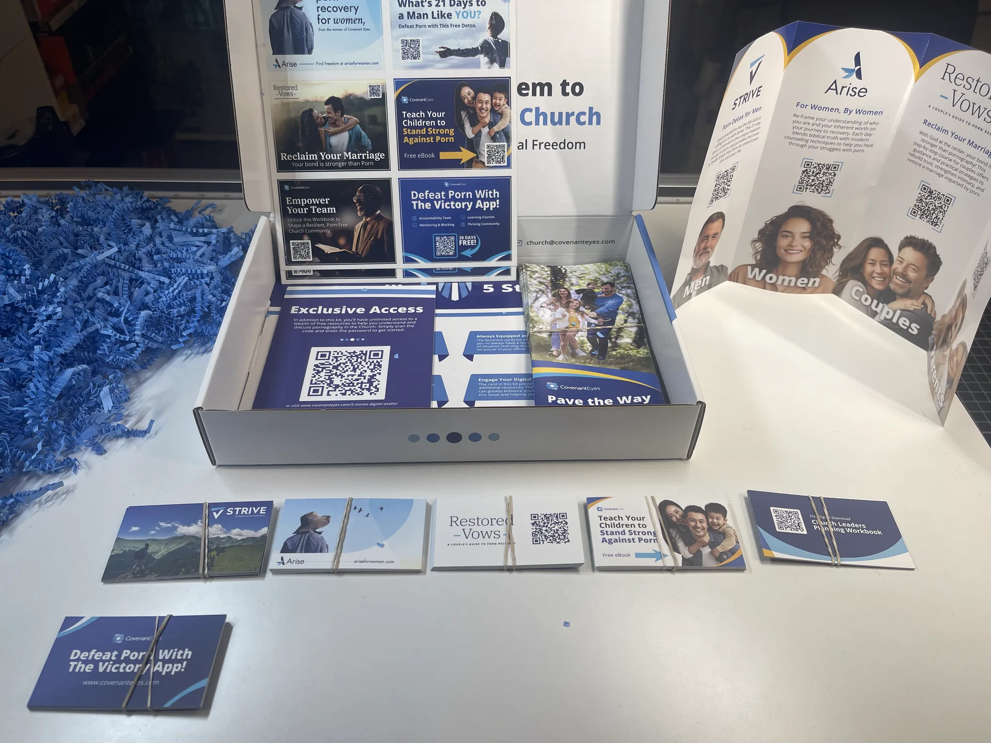 The kit components laid out on a desk: the open box, the gatefold brochure standing upright, and the resource cards in a row.